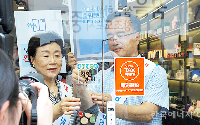 이상홍 한국에너지공단 이사장 직무대행(오른쪽)과 조종남 서울YWCA회장이 착한가게에 동의한 명동의 한 상점에서 착한가게 스티커를 부착하고 있다.