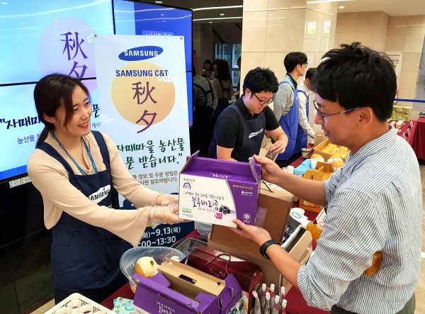 삼성물산 임직원이 직거래 장터에서 자매마을 특산품을 구입하고 있다.